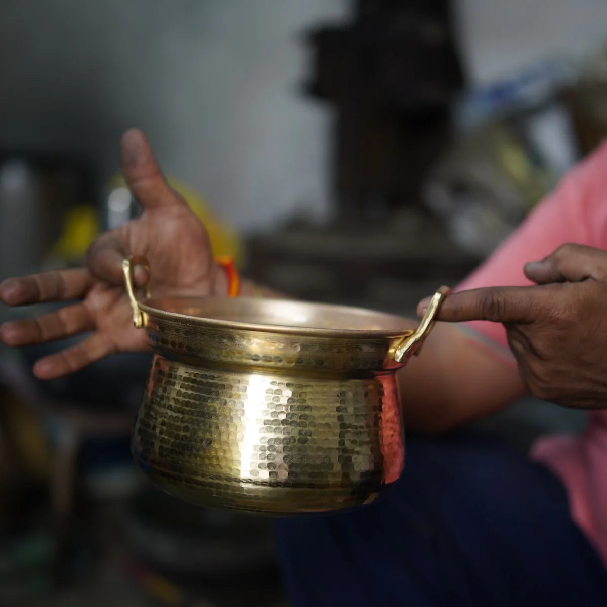 Artisan holding a Shakuntala Patra with blurred background-Zishta Traditional Brass Cookware