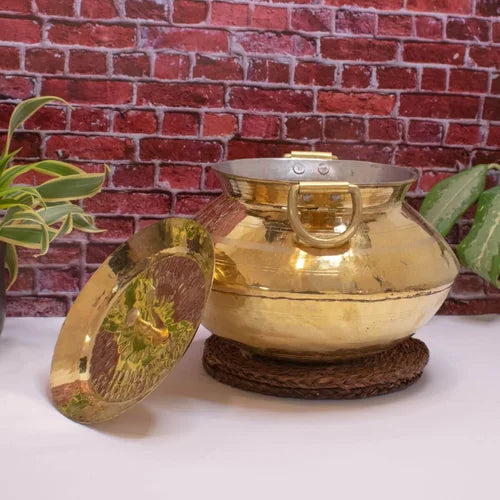Brass Handi with lid on a white surface against a brick wall background-Zishta Traditional Cookware