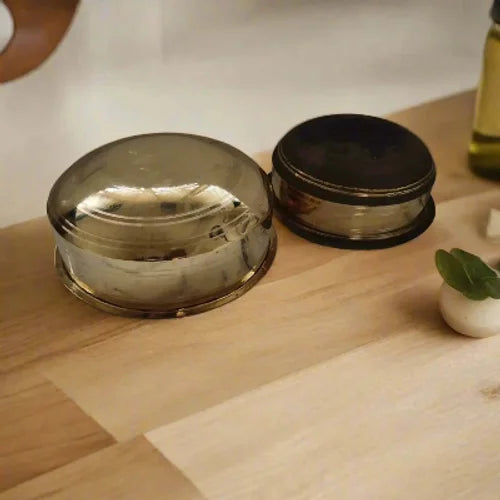 Two Brass Cooking Pot Sarva Kadais, one with natural finish bottom finish and another with polished finish on a wooden surface-Zishta Traditional Cookware