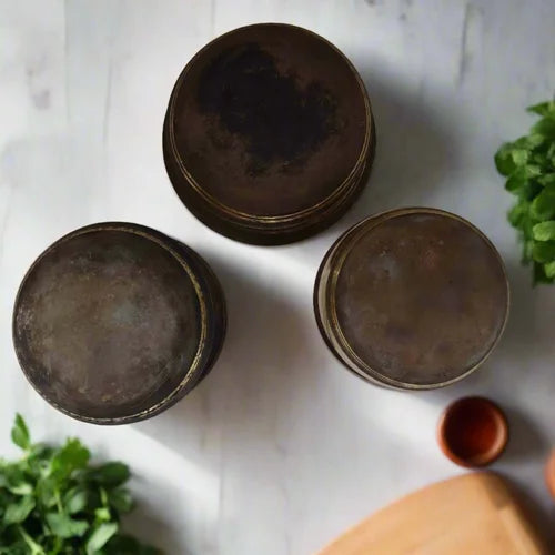 Set of 3 Three Brass Cookware with natural finish bottom on a light wooden surface with greenery-Zishta Traditional Cookware