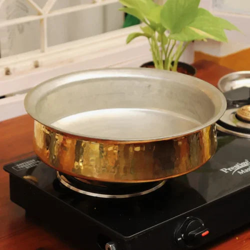 Brass Lagan on a stove with a plant in the background-Zishta Traditional Cookware