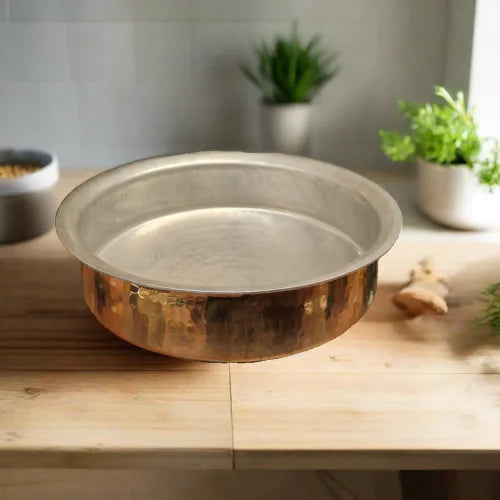 Brass Lagan on a wooden surface with plants in the background-Zishta Traditional Cookware