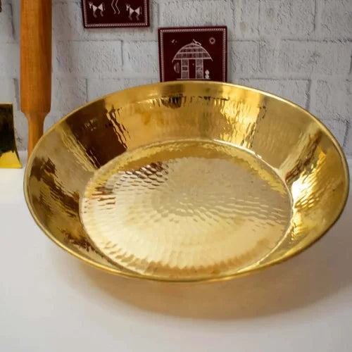 Brass Paraat on a white surface with a light gray textured wall in the background-Zishta Traditional Kitchen Accessories