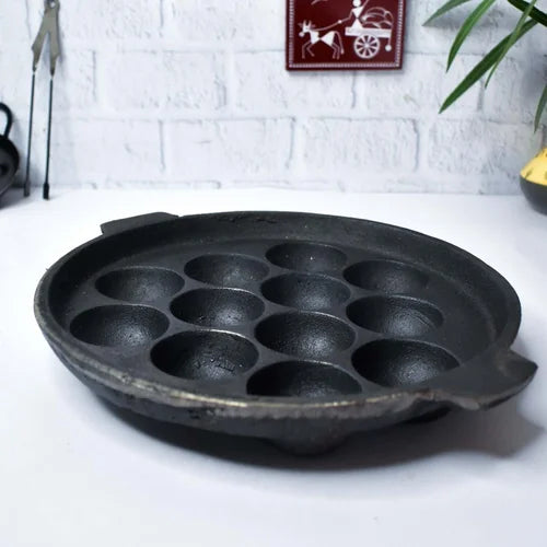Cast iron Kuzhipaniyara Kal-Appe Paddu Tawa-pan with 12 cavities on a white surface-Zishta Traditional Cookware
