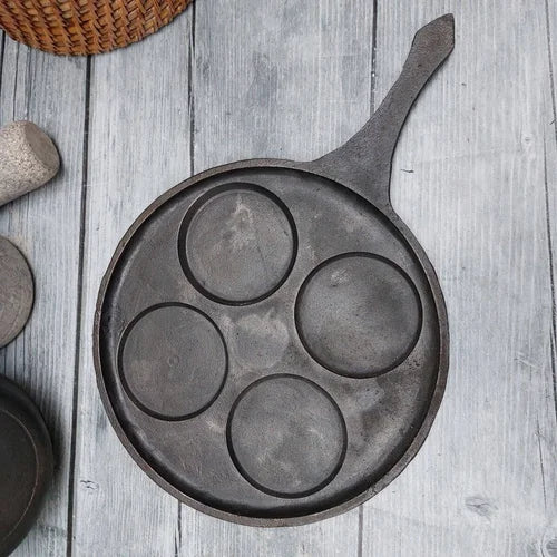 Cast iron mini uthappam pan with four cavities on a wooden surface-Zishta Traditional Cookware