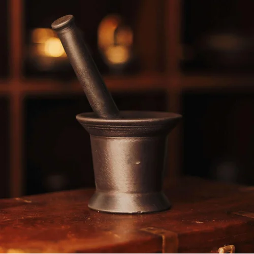 Cast Iron metal mortar and pestle on a wooden surface with a blurred background-Zishta Traditional Kitchen Accessories