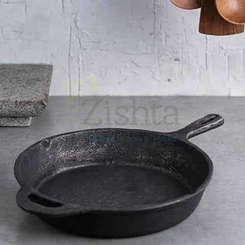 Black cast iron skillet on a gray surface with a neutral background-Zishta Traditional Cookware