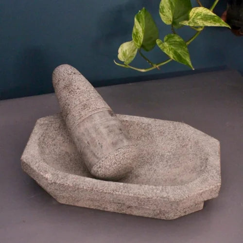Traditional Granite Stone mortar and pestle on a gray surface with a plant in the background-Zishta Kitchen Accessoires