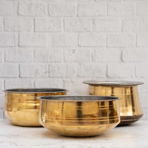 Three brass cookware on a white surface with a white brick wall background-Zishta Traditional Cookware