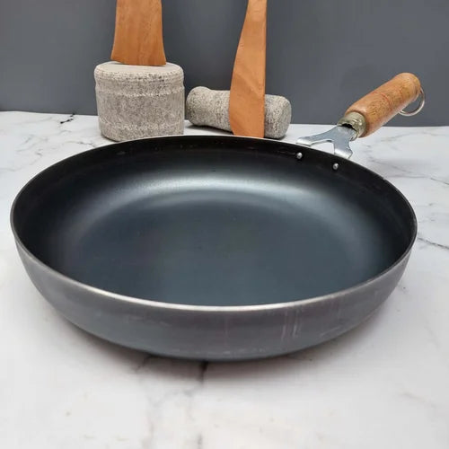 Pure Iron frying pan with wooden handle on a marble surface-Zishta Traditional Cookware
