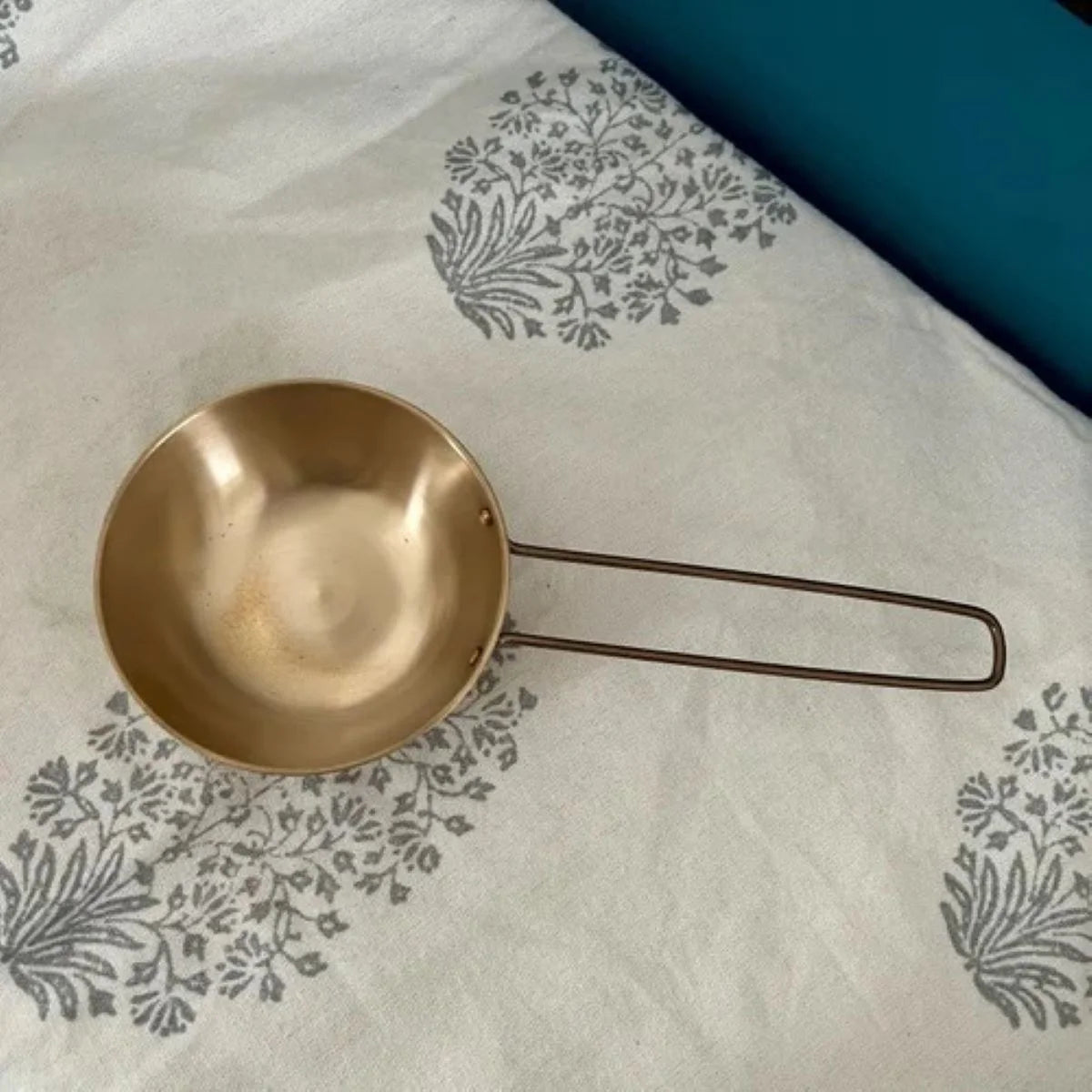 Bronze Kansa Tadka Pan on a white cloth with gray floral patterns-Zishta Kitchen Accessories