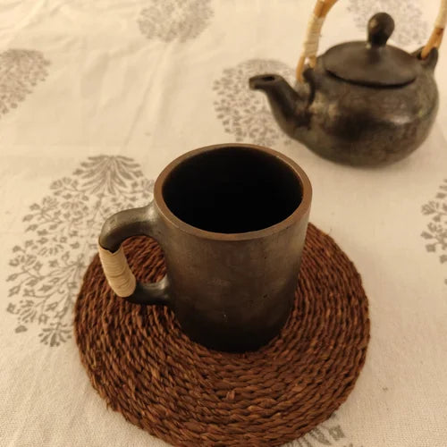 Manipur Black Pottery Milk Cup and teapot on a textured surface with a woven coaster-Zishta Traditional Serveware