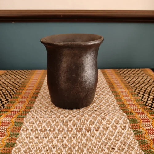 Manipur Black Pottery Water Mug on a textured surface with a blurred background-Zishta Traditional Serveware