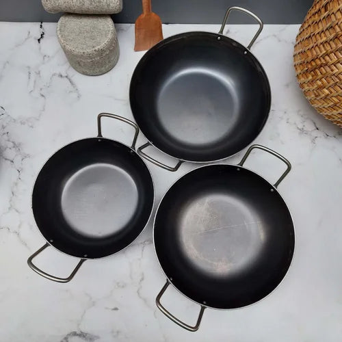 Three black iron flat bottom kadai frying pans with handles on a marble surface-Zishta Traditional Cookware