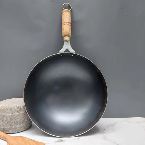 Iron wok with a wooden handle on a gray background-Zishta Traditional Cookware