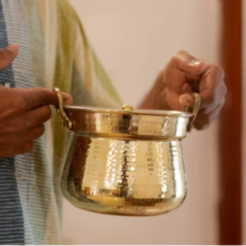 Person holding a Shakuntala Patra with a blurred background-Zishta Traditional Brass Cookware