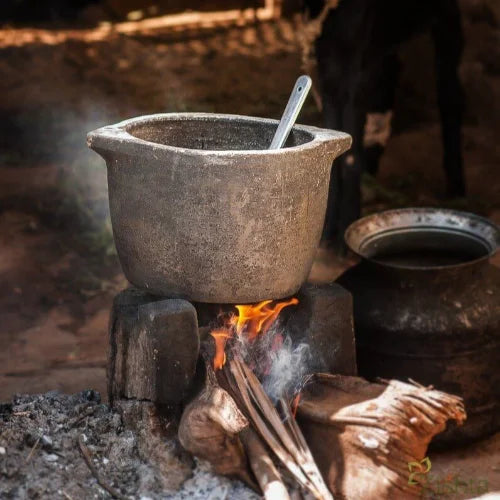 Soapstone Kalchatti Cookware over an open fire with a spoon inside, rustic setting-Zishta Traditional Cookware