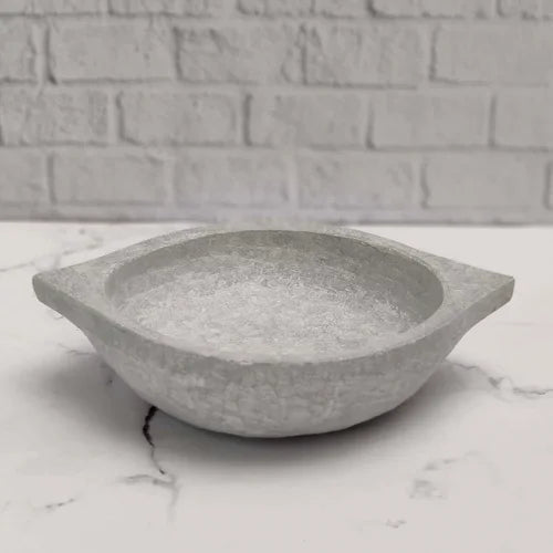 Soapstone Kadai on a marble surface with a brick wall background-Zishta Traditional Cookware