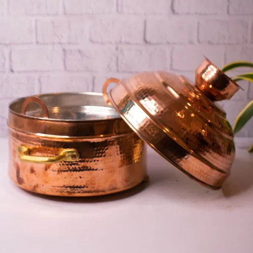 Handcrafted Copper Modak Patra with lid on a white surface with a light gray brick wall background-Zishta Traditional Cookware
