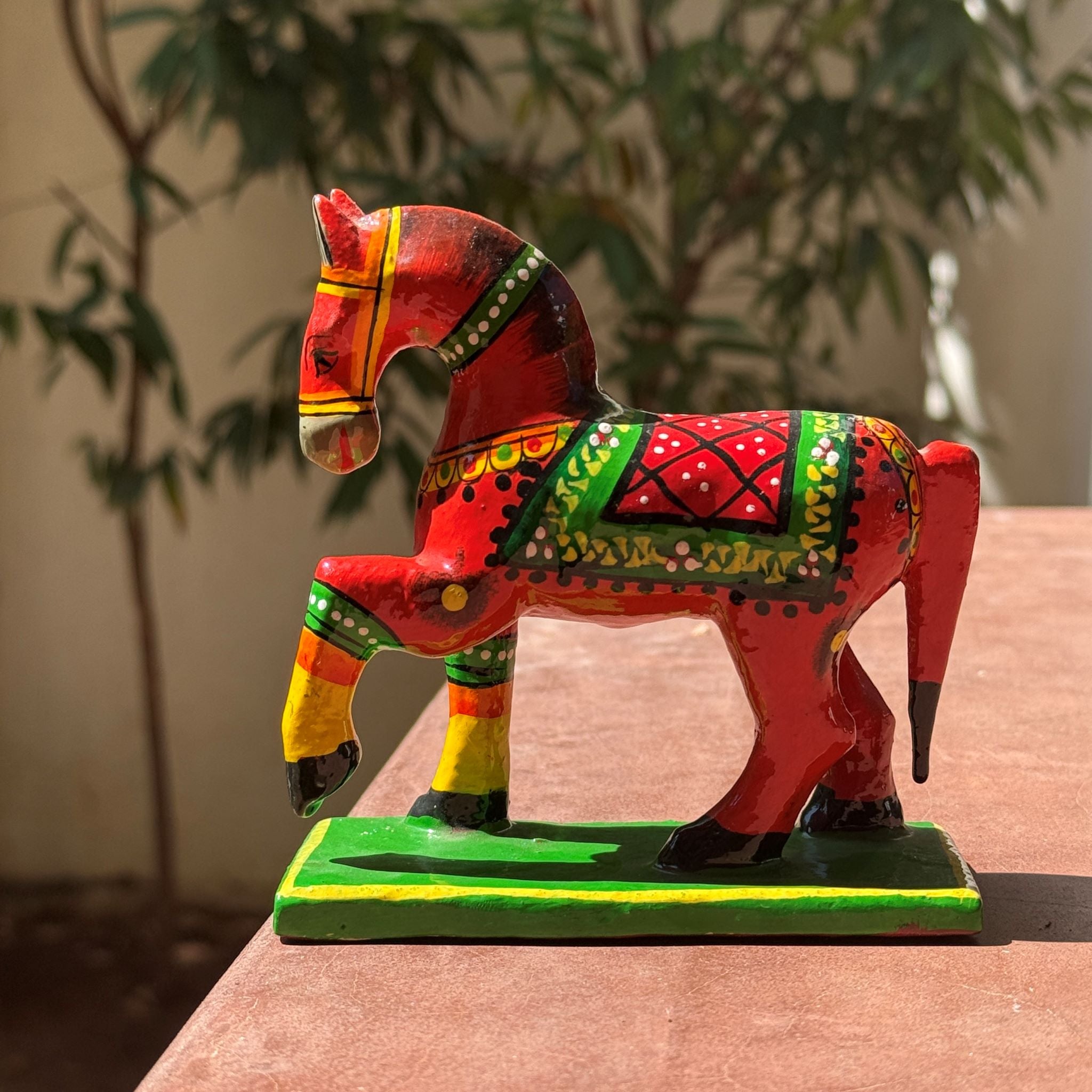 Colorful horse figurine on a wooden surface with a blurred plant background-Zishta Traditional Home Decor-Dolls and Toys