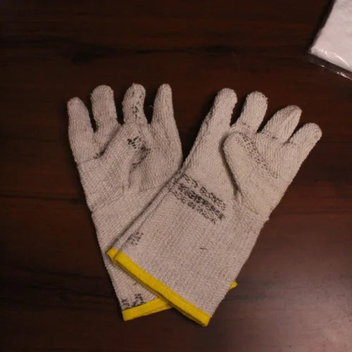 Zishta Kalai Kit Accessoires-Pair of beige gloves with yellow trim on a wooden surface