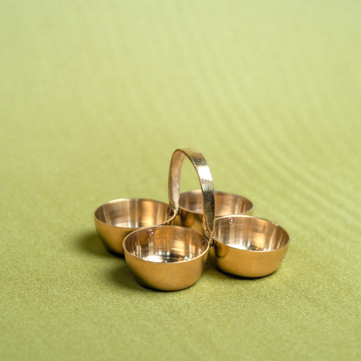 Brass Pooja Chowmukh-Set of four brass bowls with a handle on a green background-Zishta Traditional Decor-Navratri Gifting