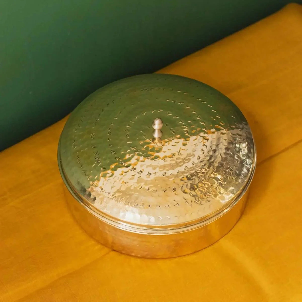 Brass Spice Box with lid on a yellow surface against a green background-Zishta Traditional Kitchen Storage Containers