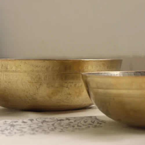 Two brass tasla kadais on a textured surface with a neutral background-Zishta Traditional Cookware
