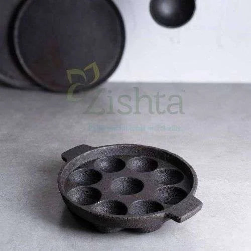 Cast iron Kuzhi paniyaram Kal-Paddu pan with 9 cavities on a gray surface,-Zishta Traditional Cookware