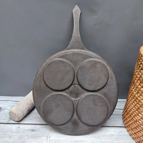 Cast iron pancake pan with four circular compartments on a wooden surface-Zishta Traditional Cookware