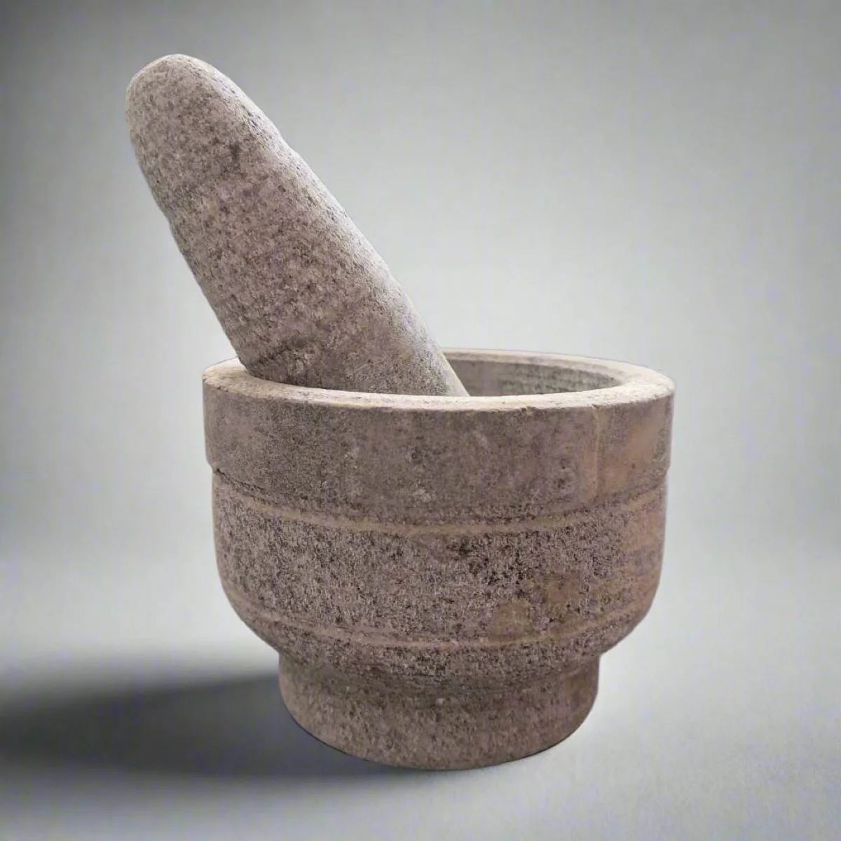 Stone mortar and pestle on a gray background-Zishta Kitchen 