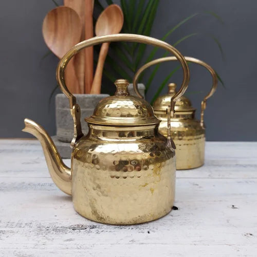 Brass Kettle-teapot on a wooden surface with wooden spoons and a plant in the background-Zishta Traditional Serveware