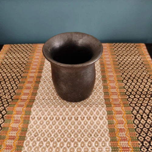 Manipur Black Pottery Water Mug on a textured woven surface with a blue wall background-Zishta Traditional Serveware