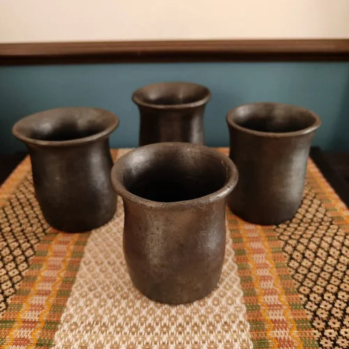 Four Manipur Black Pottery Mugs on a textured surface with a blurred background-Zishta Traditional Serveware