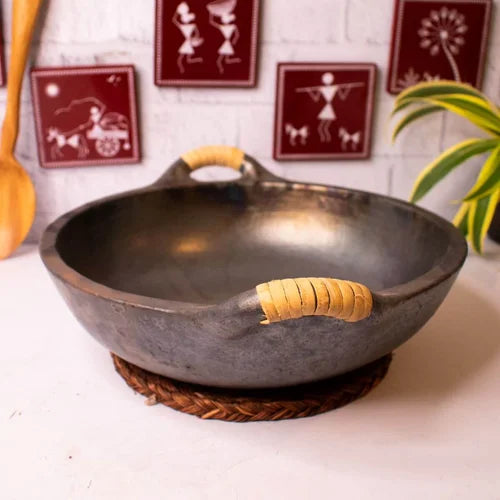 Manipur Black Pottery Open Kadai with yellow handles on a white surface, with decorative elements in the background-Zishta Traditional Cookware
