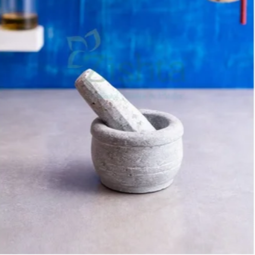 Soapstone mortar and pestle on a gray surface with a blue abstract background-Zishta Traditional Kitchen Accessories